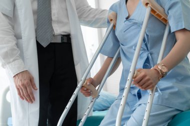 Doktor hastanede koltuk değnekli hastayla ilgileniyor.