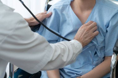 Profesyonel üniformalı doktor hastanedeki hastayı muayene ediyor.