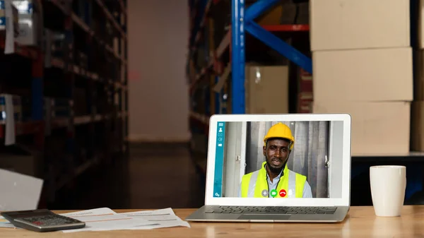 Warehouse staff talking on video call at computer screen in storage warehouse