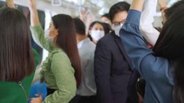 Kalabalık bir metroda maske takan insanlar.