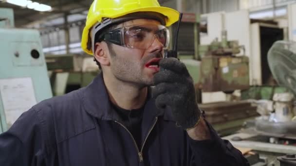 機械部品を検査しながら携帯ラジオで話す工場労働者 — ストック動画
