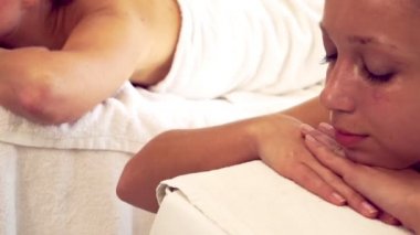 Rahatlamış genç bir kadın masaj için spa yatağında yatıyor..