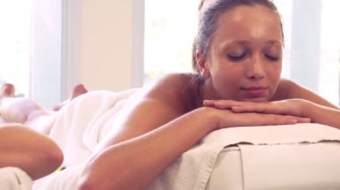 Rahatlamış genç bir kadın masaj için spa yatağında yatıyor..