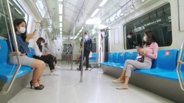 Kalabalık bir metroda maske takan insanlar.