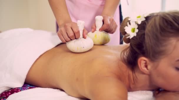 Massage therapist using herbal compress on woman. — Stock Video