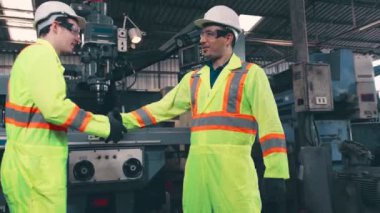 Fabrika işçileri fabrikadaki ekip üyeleriyle tokalaşıyor.