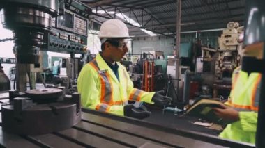 Fabrika atölyesinde makine ekipmanı kullanan bir grup işçi.