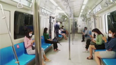 Kalabalık bir metroda maske takan insanlar.