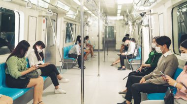 Kalabalık bir metroda maske takan insanlar.