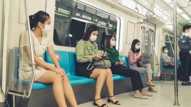 Kalabalık bir metroda maske takan insanlar.