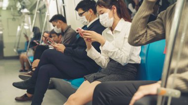 Kalabalık bir metroda maske takan insanlar.