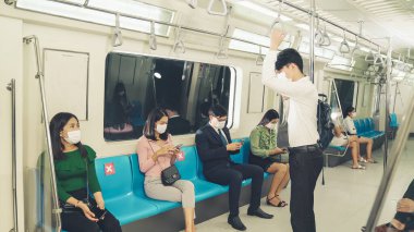 Kalabalık bir metroda maske takan insanlar.
