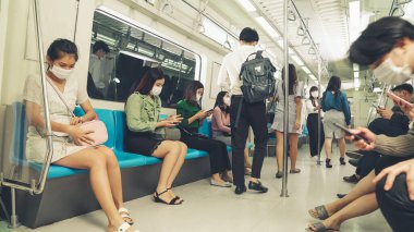 Kalabalık bir metroda maske takan insanlar.