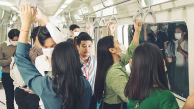 Kalabalık bir metroda maske takan insanlar.