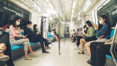 Kalabalık bir metroda maske takan insanlar.