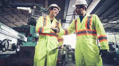 Fabrika işçileri fabrikadaki ekip üyeleriyle tokalaşıyor.