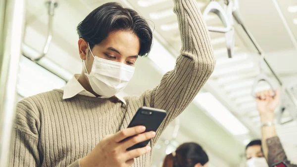 Reisender trägt Gesichtsmaske bei Handynutzung in S-Bahn — Stockfoto