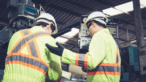 Group of factory workers using machine equipment in factory workshop