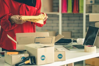 Çevrimiçi satıcı ev ofisinde çalışıyor ve teslimat kutusunu müşteriye paketliyor..