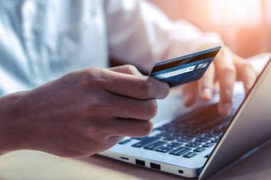 Genç adam online alışveriş için kredi kartı kullanıyor.