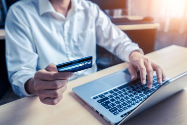 Genç adam online alışveriş için kredi kartı kullanıyor.