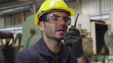 Fabrika işçisi, makine parçalarını incelerken taşınabilir radyodan konuşuyor.