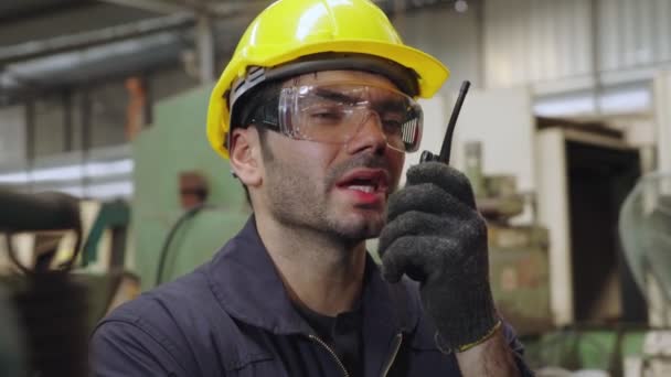 Fabriksarbetare som talar på bärbar radio medan de inspekterar maskindelar — Stockvideo
