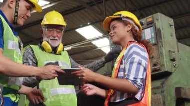 Fabrika atölyesinde makine ekipmanı kullanan bir grup işçi.