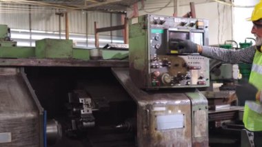 Fabrika işçisi fabrika atölyesinde makine teçhizatı kullanmayı öğretiyor.