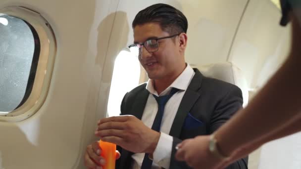 У бизнесмена есть апельсиновый сок, подаваемый стюардессой в самолете. — стоковое видео