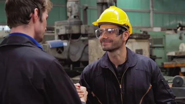 Tired factory workers taking a break and talking to coworker in the factory