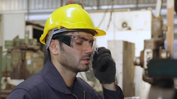Trabalhador da fábrica falando em rádio portátil enquanto inspeciona peças de máquinas — Fotografia de Stock