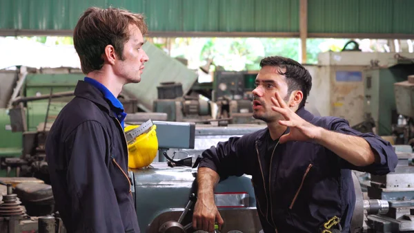 Tired factory workers taking a break and talking to coworker in the factory