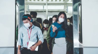 Kalabalık bir metroda maske takan insanlar.