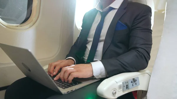 Jovem empresário usando computador portátil no avião — Fotografia de Stock