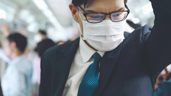 Junger Mann mit Gesichtsmaske fährt in überfüllter U-Bahn — Stockfoto