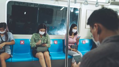 Kalabalık bir metroda maske takan insanlar.