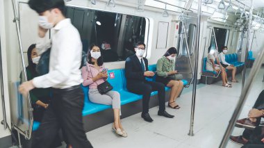 Kalabalık bir metroda maske takan insanlar.