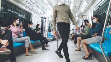 Kalabalık bir metroda maske takan insanlar.