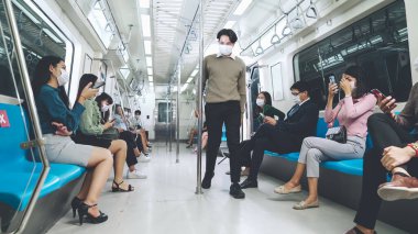 Kalabalık bir metroda maske takan insanlar.