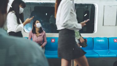 Kalabalık bir metroda maske takan insanlar.