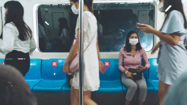 Kalabalık bir metroda maske takan insanlar.