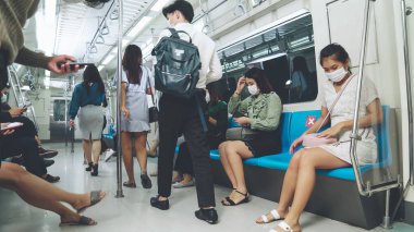 Kalabalık bir metroda maske takan insanlar.