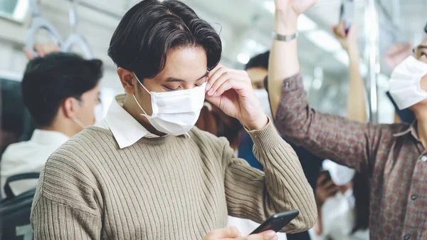 Pelancong mengenakan masker wajah saat menggunakan ponsel di kereta api umum — Stok Foto