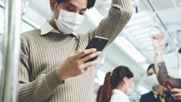 Viajero con máscara facial mientras usa el teléfono móvil en el tren público —  Fotos de Stock