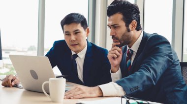 İki iş adamı ofiste proje stratejisi hakkında konuşuyor