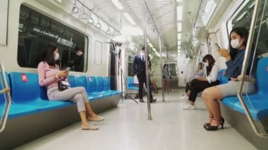 Kalabalık bir metroda maske takan insanlar.