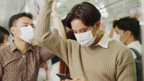 Viajero con máscara facial mientras usa el teléfono móvil en el tren público — Vídeos de Stock