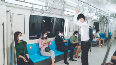 Kalabalık bir metroda maske takan insanlar.