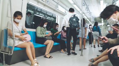 Kalabalık bir metroda maske takan insanlar.